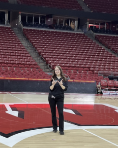 A woman smiles while standing on the Wisconsin basketball court. 